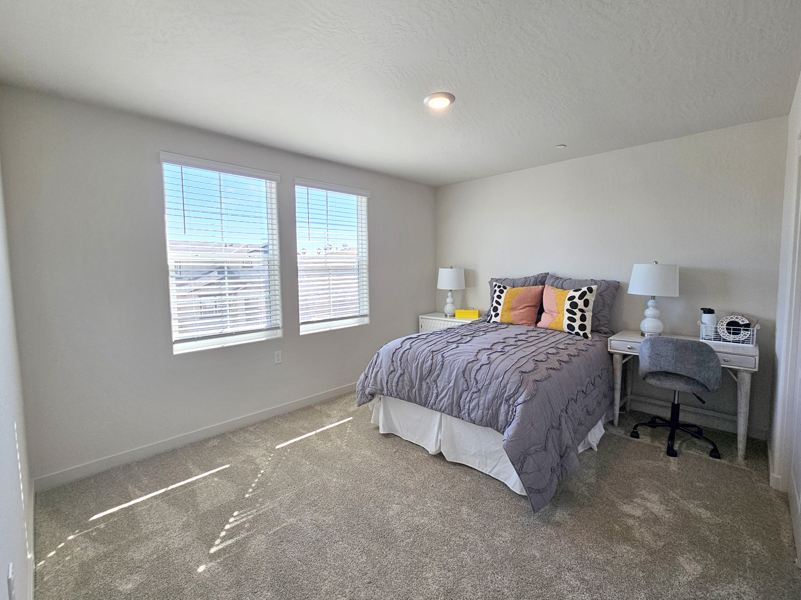 A bedroom with a bed desk and a lamp.