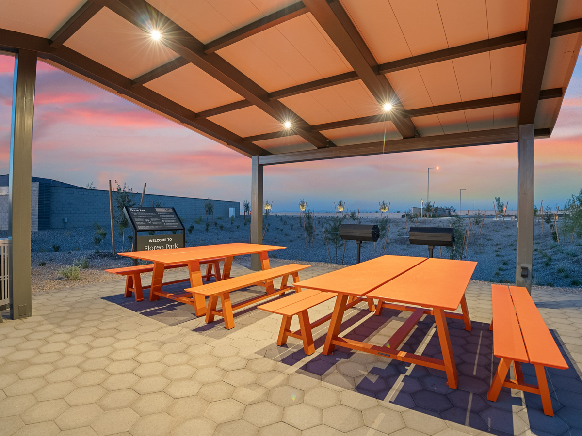 A group of tables and chairs on a patio by the water.