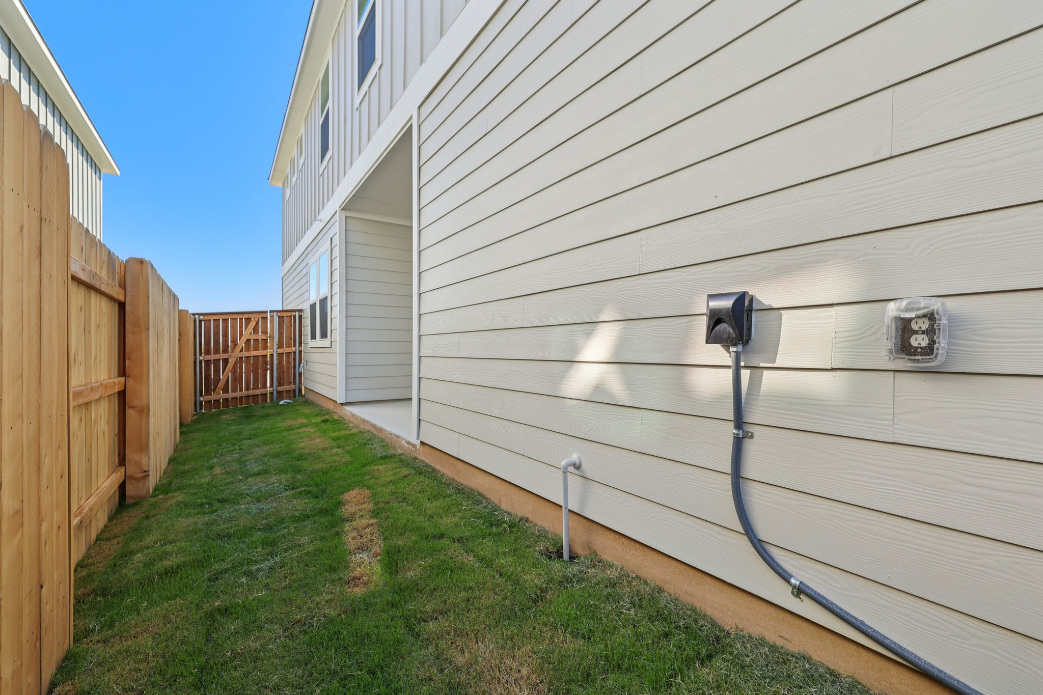 A backyard with a fence and a lawn.