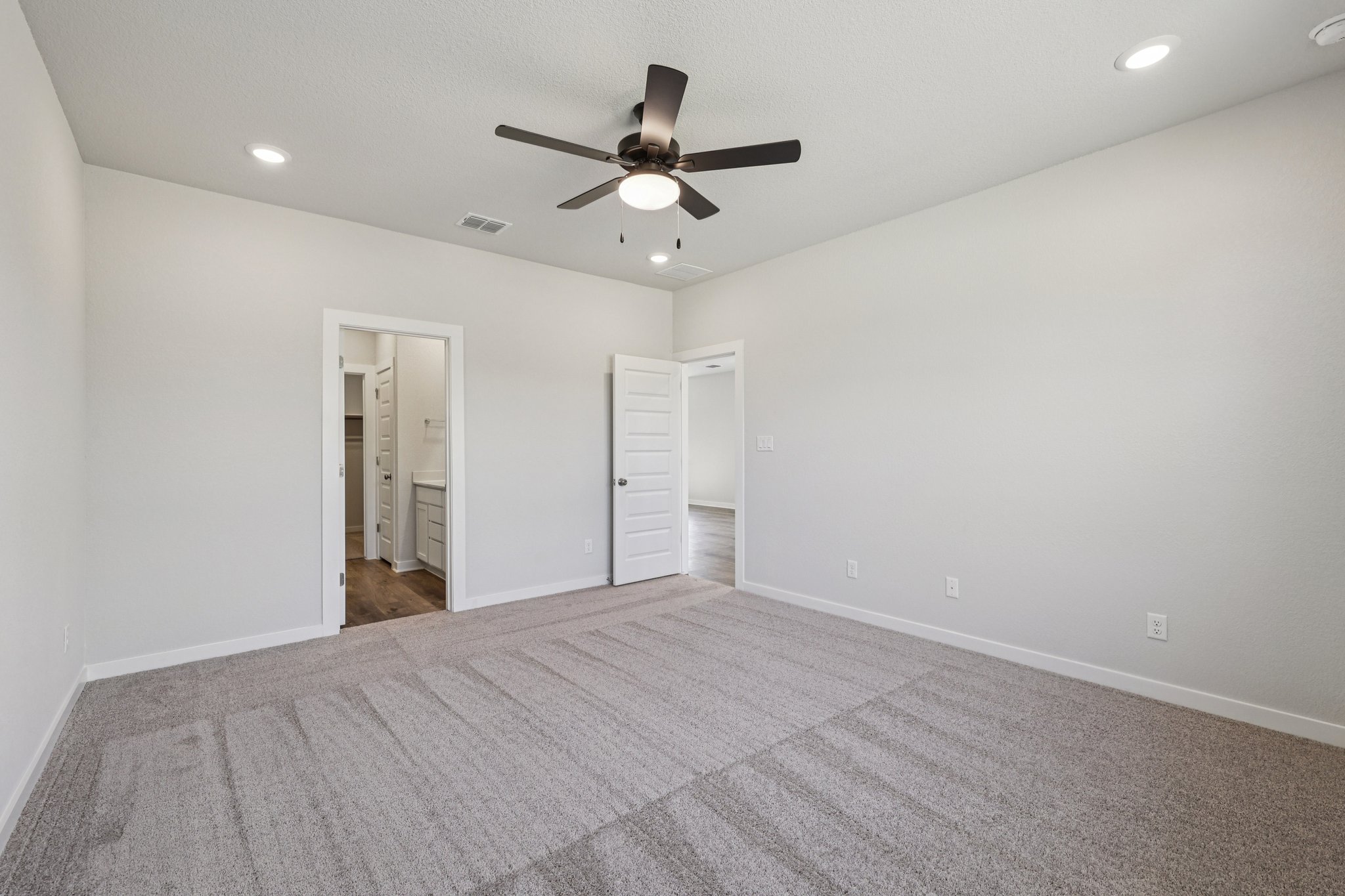 A room with a ceiling fan and a carpet.