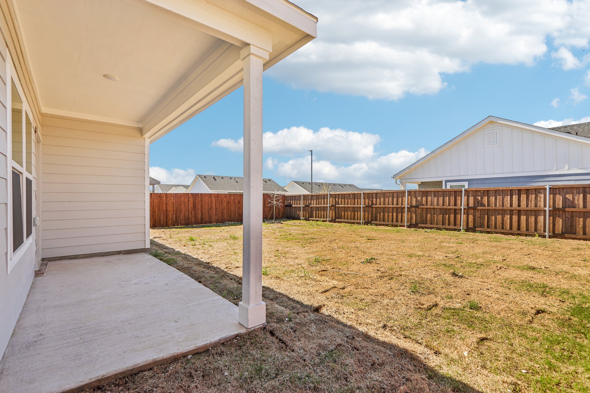 A fenced in yard with a house and a wood fence.