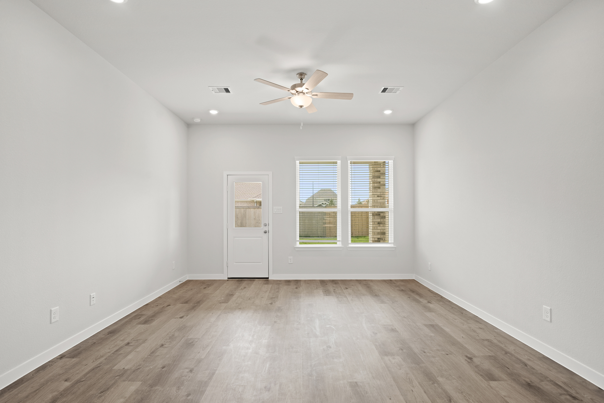 A room with a ceiling fan and a wood floor.