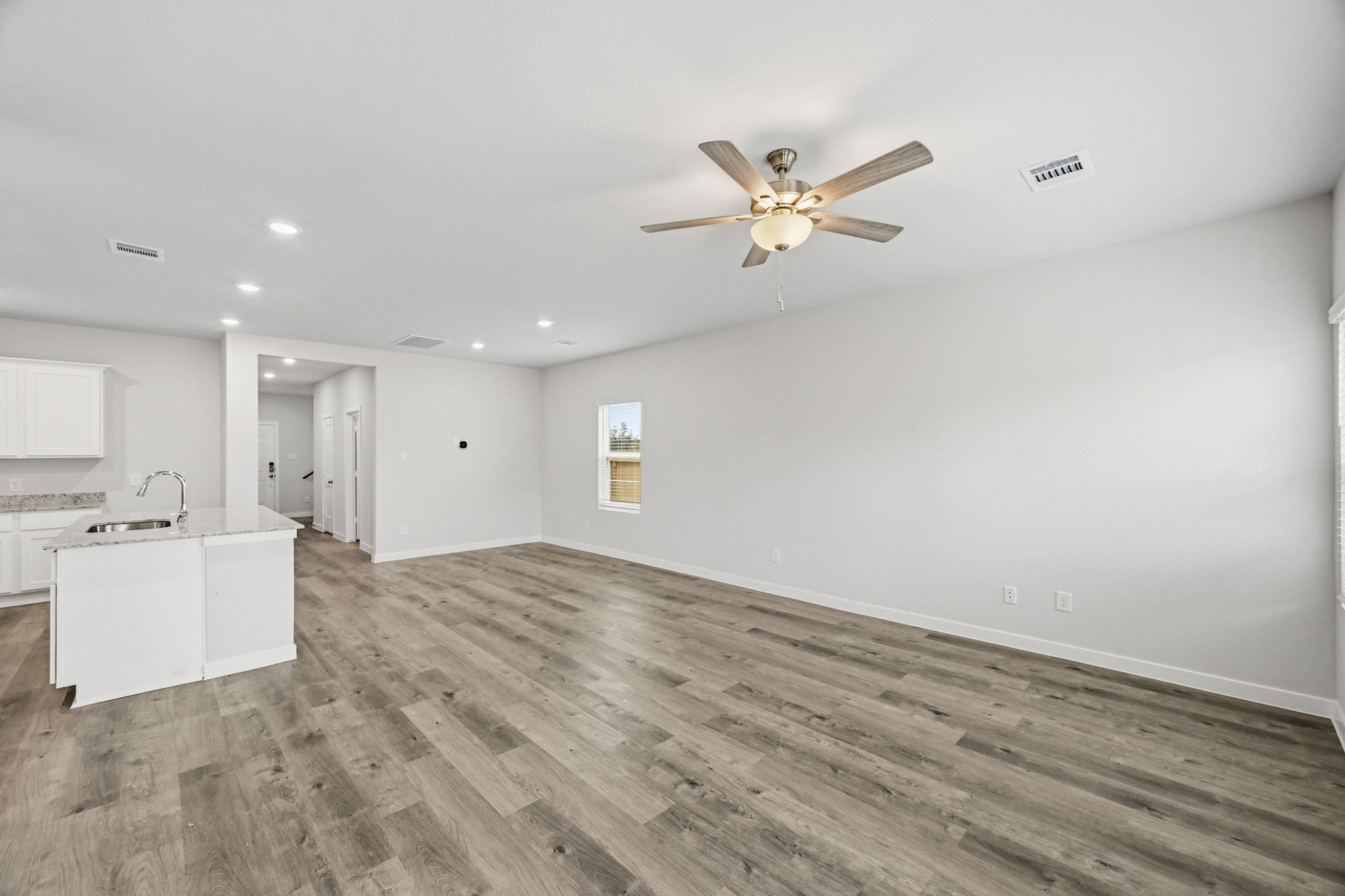A large empty room with a ceiling fan and a wood floor.