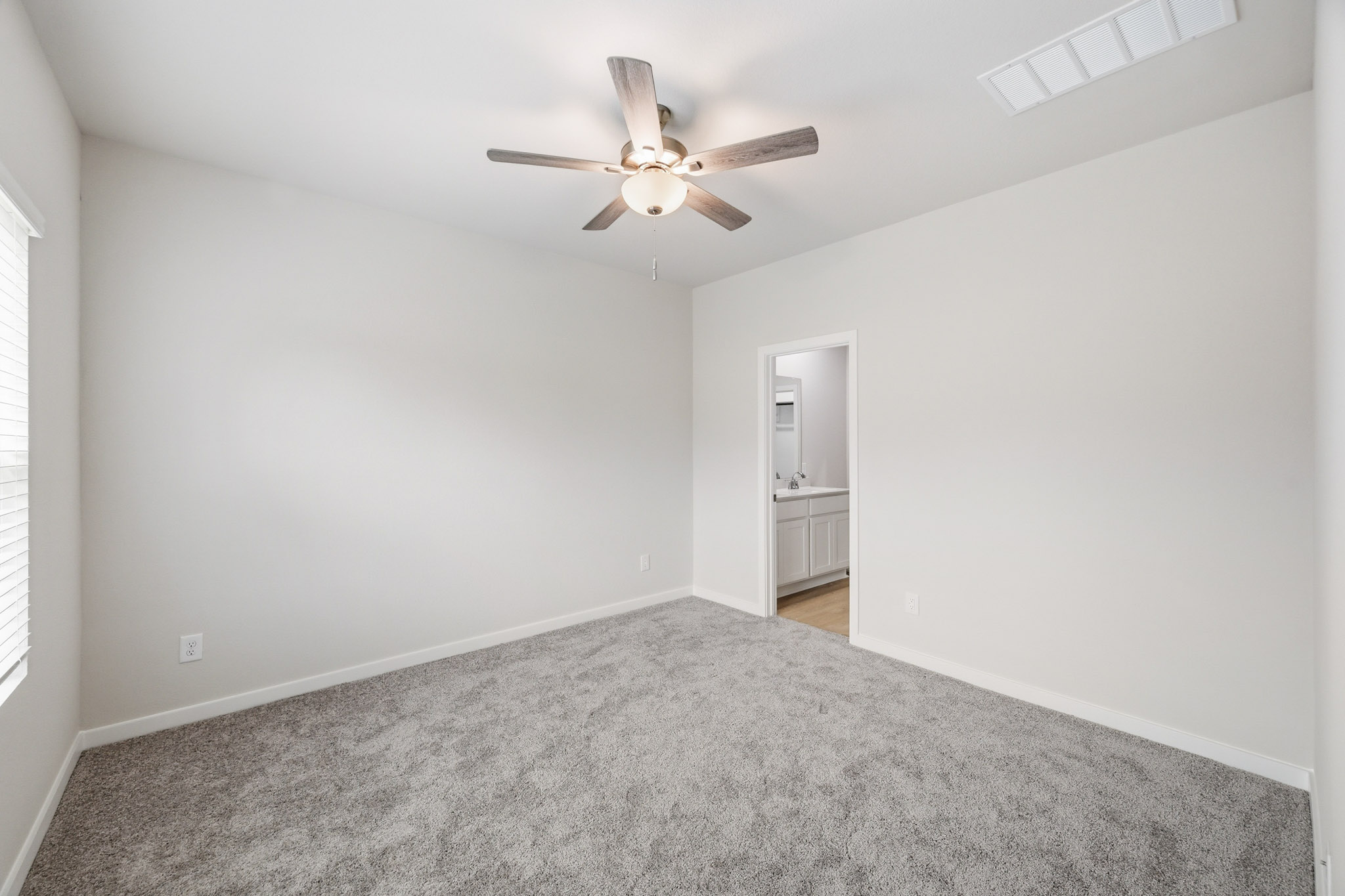 A room with a ceiling fan and a carpet.