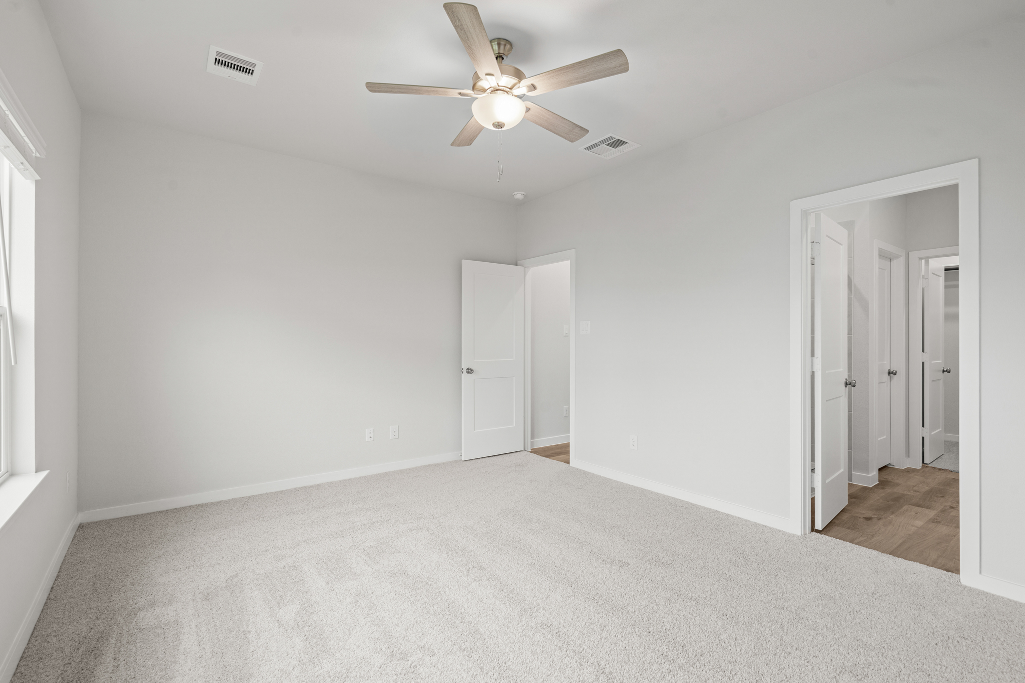 A room with white walls and a ceiling fan.
