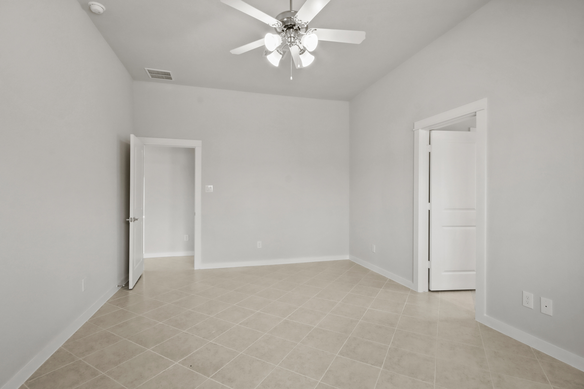 A room with a ceiling fan and a door.