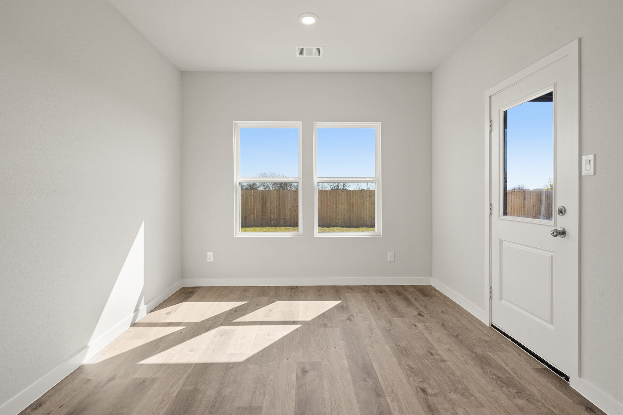 A room with a wood floor and a white door with a window.