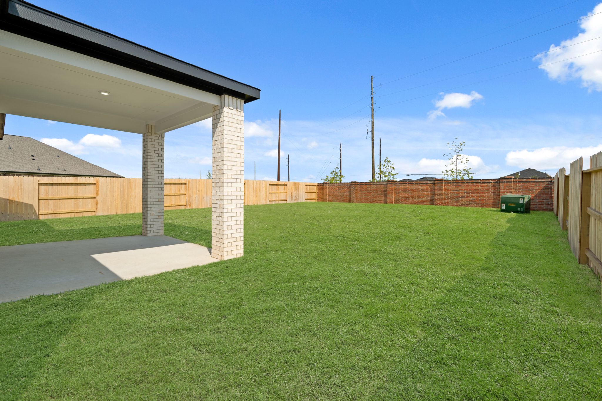A green lawn with a brick wall and a building in the background.