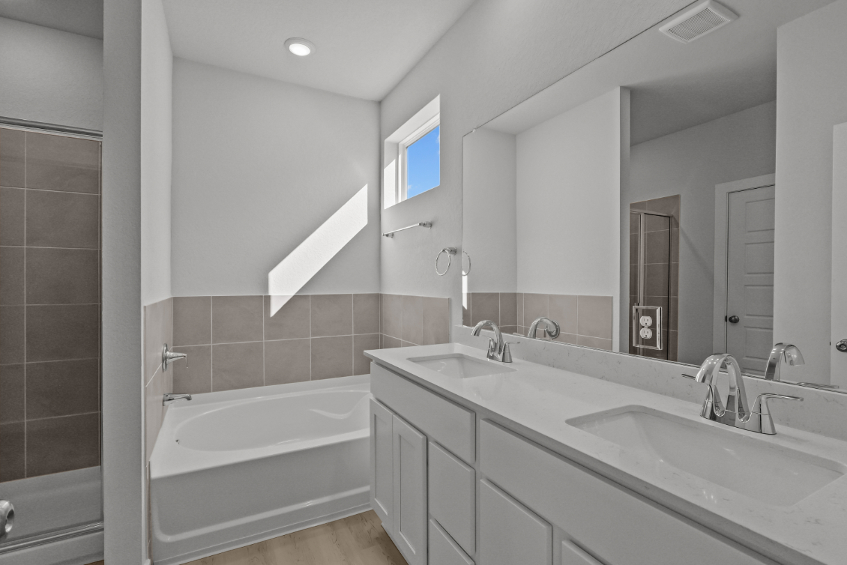 A bathroom with a tub sink and mirror.