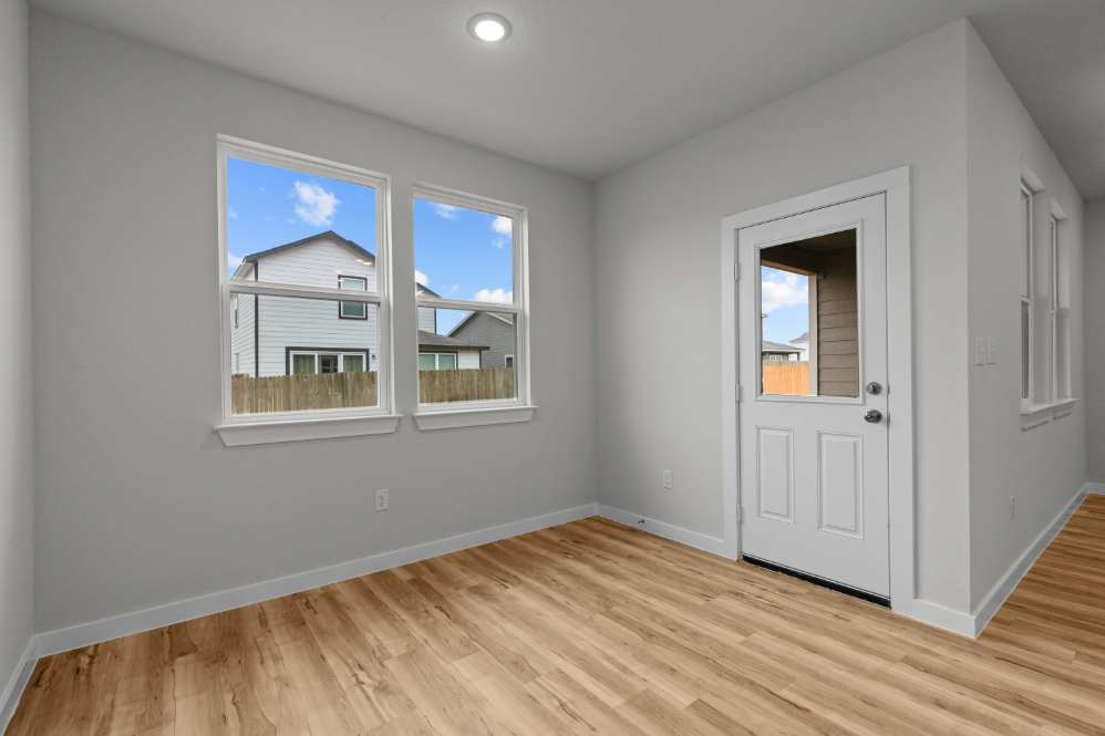 A room with a wood floor and a white door with a window.