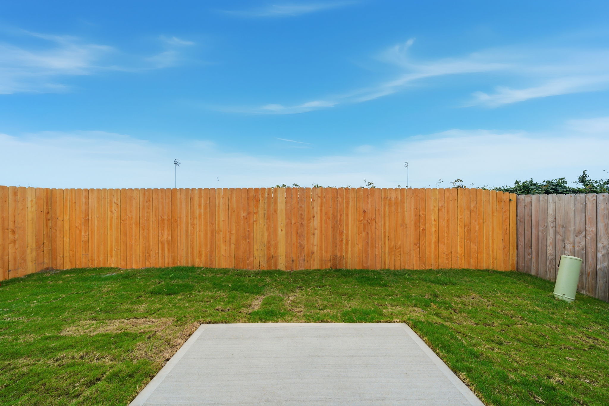 A fenced in yard with a white table and a wood fence.