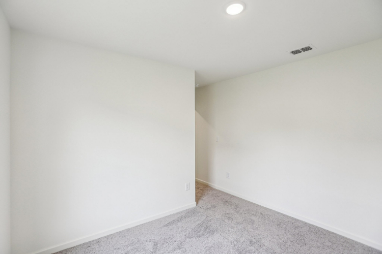 A room with a carpet and a light on the wall.