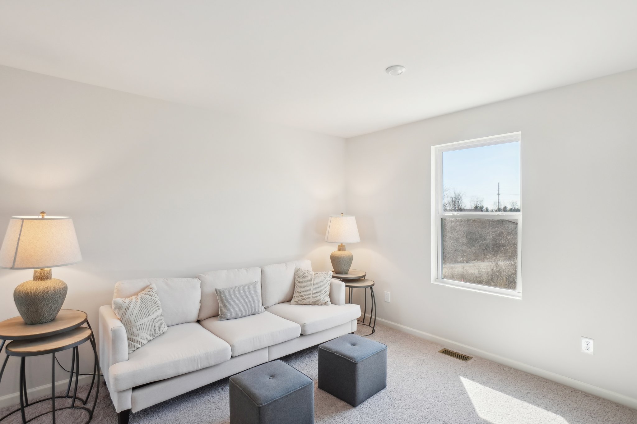 A living room with a white couch and a window.