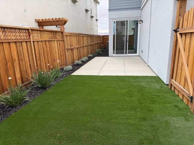 A backyard with a fence and a house.